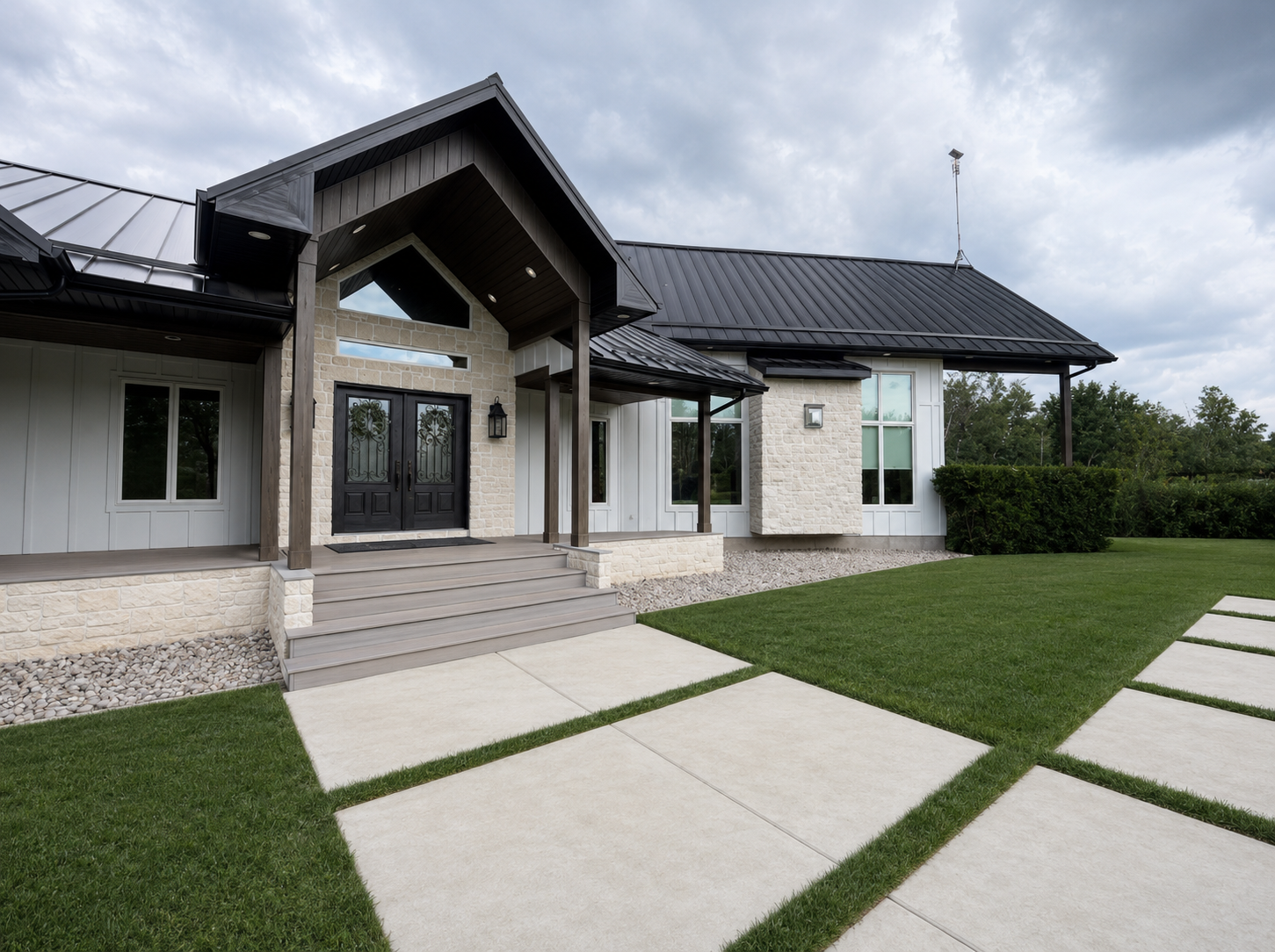 New home exterior with stone accents, black metal roof and landscaped entrance
